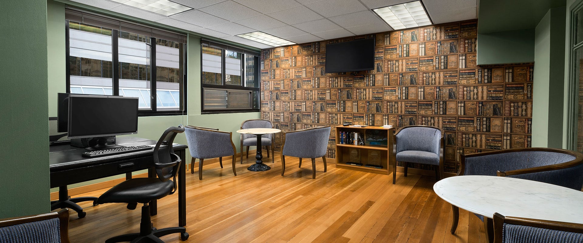 The Business Centre at Days Inn Vancouver Downtown offers comfortable tub chairs in blue fabric, a black computer table and desktop, round tables and wall mounted flatscreen TV.