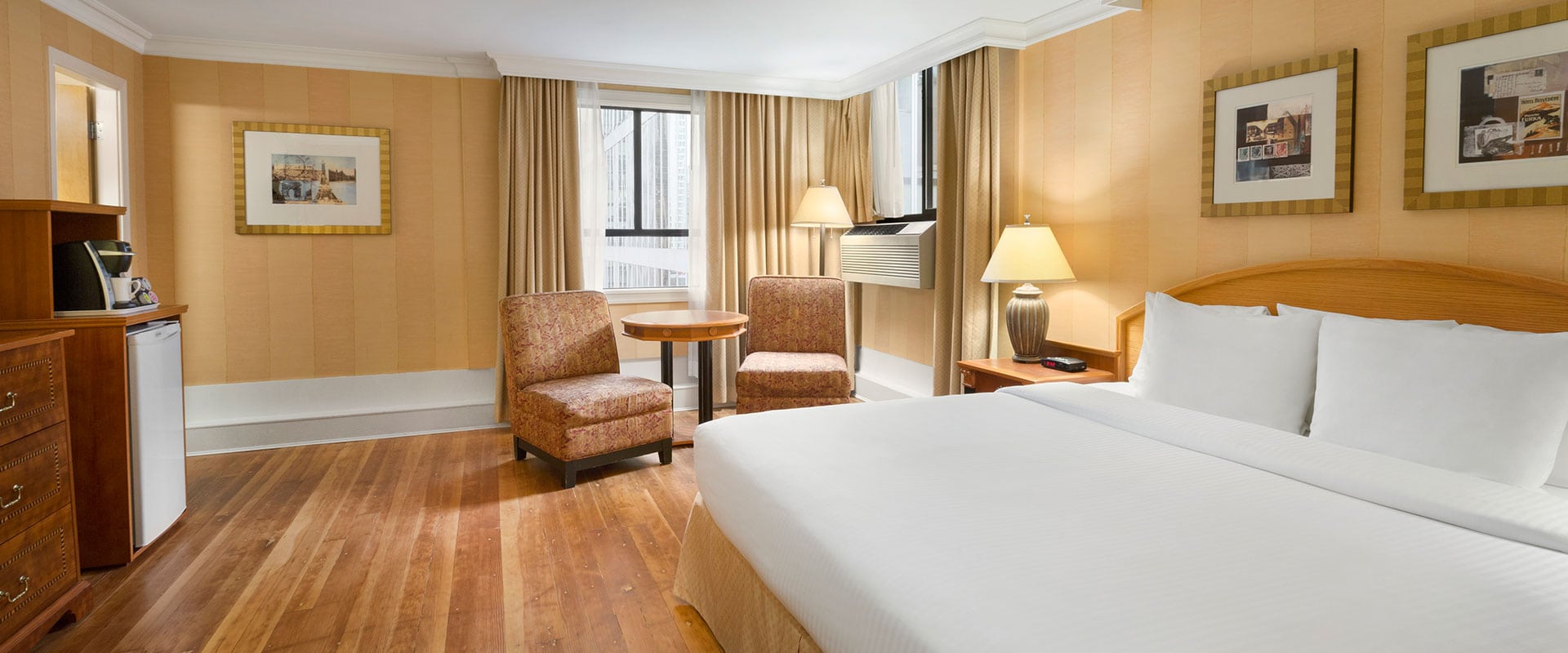 The Standard Queen suite painted in gold-yellow offers amenities such as coffee maker, mini refrigerator and air conditioner for guests at Days Inn Vancouver Downtown.