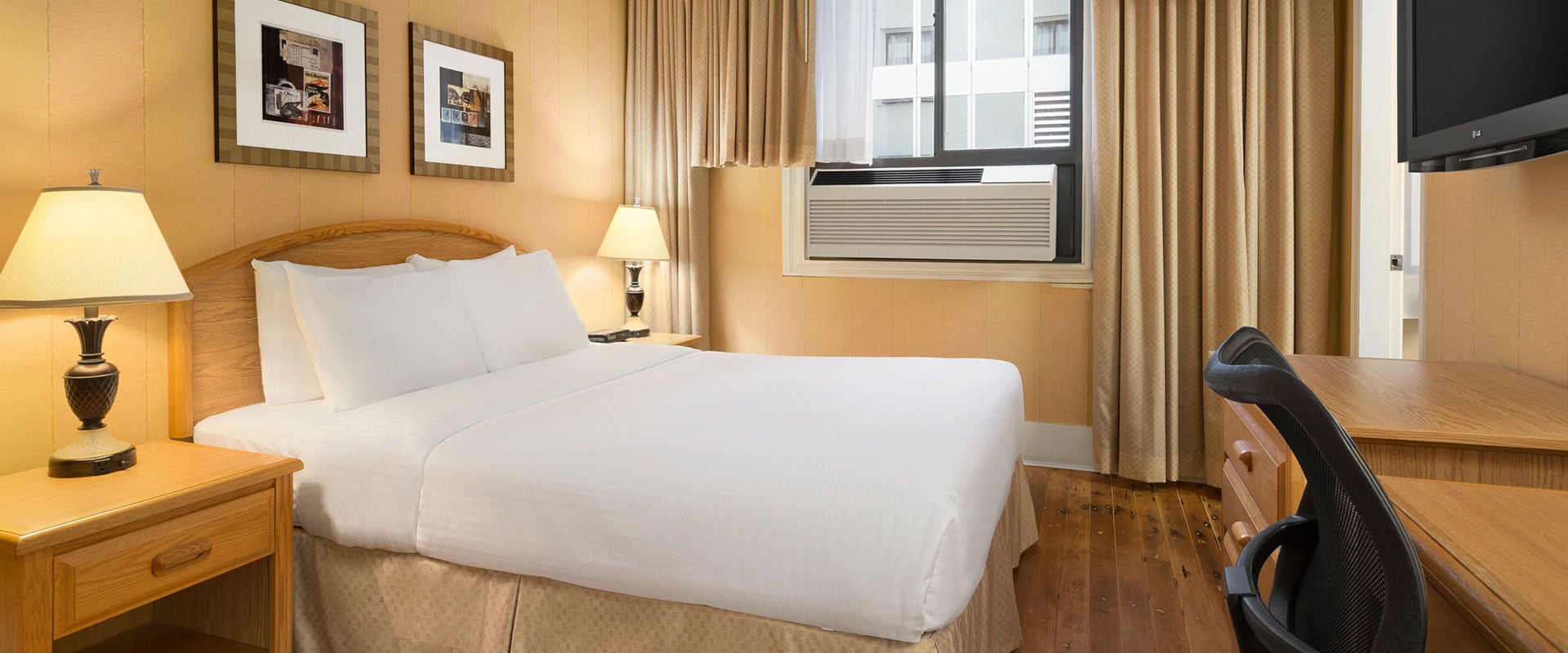The Standard Double suite includes a wall mounted flatscreen TV, writing desk and chair, two beside tables and lamps and air conditioning at Days Inn Vancouver Downtown.