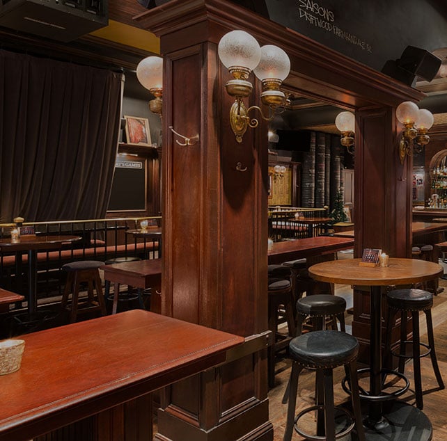 The Butcher and the Bullock pub in Vancouver Downtown has original wood flooring, rich red wood paneling, round black leather barstools and round tables.
