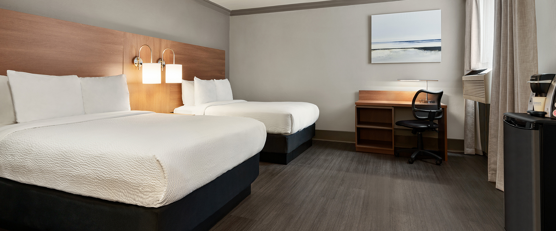 Standard Two Doubles suite at Days Inn Vancouver Downtown, features gold-yellow painted walls, two double beds, hardwood floors, a writing desk and leather padded chair.